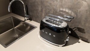 A kitchen with a modern stainless steel sink and a black toaster branded 'SMEG'. - Apartment 'Boutique Yellow' with Balcony, Wi-Fi and Air Conditioning (Nago-Torbole)