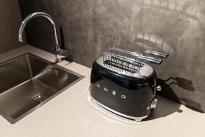 Una cucina con un lavello moderno in acciaio inox e un tostapane nero marca SMEG.