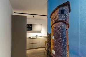 Une cuisine moderne dotée d’un îlot central, d’un coin repas avec une chaise et d’une fresque représentant une tour.