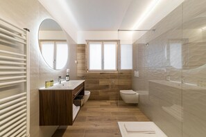 Un bagno moderno con un mobile lavabo in legno, cabina doccia in vetro e uno specchio grande.