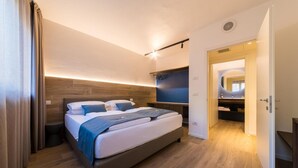 Un dormitorio moderno con cama, mesitas de noche, televisor empotrado y vestidor.