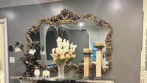 A marble console table with a large ornate mirror, a vase of flowers, and a framed painting. - Peaceful Lakeside Escape• Trails & Parks Nearby (Grimsby)