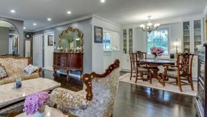 A spacious living room with a large sofa, a dining area with a chandelier, and a mirrored wall. - Peaceful Lakeside Escape• Trails & Parks Nearby (Grimsby)