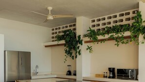 A modern kitchen with a central island, wooden chairs, a refrigerator, a microwave, and ceiling fans. - Luxury Oceanfront Double Villa With Pool (Puerto Escondido)