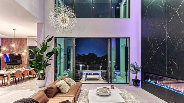 Uma sala de estar moderna com um sofá, mesa de centro e uma grande planta em vaso.