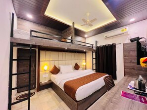 A modern hotel room with a bunk bed, a desk with a chair, a coffee maker, and a ceiling fan. - Hotel Gulmarg Residency (Mount Abu)
