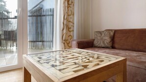 Ein Wohnzimmer mit einem Couchtisch aus Glas, der große Buchstaben zeigt, einer braunen Ledersofa und Blick durch eine Glastür.