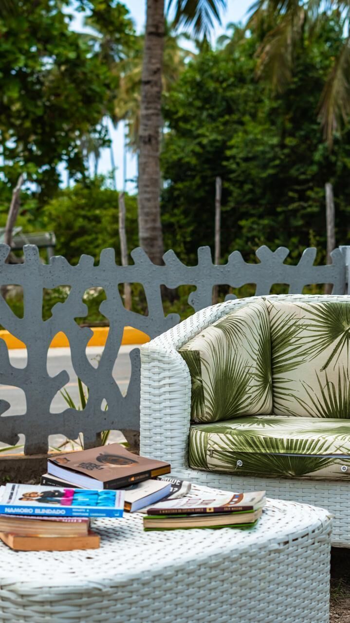 A wicker outdoor seating area with a white cushioned chair and a round table with books.