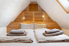 A cozy attic bedroom with wooden walls, a sloped ceiling, and two beds with checkered bedding. - Apartment "Tanne" with Shared Garden and Wi-Fi (Sasbachwalden)