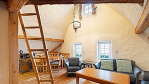 Un espacio tipo loft con escalera de madera, sofá, mesa y candelabro.