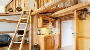 Una cocina rústica con vigas de madera, una escalera de madera y un hervidor.