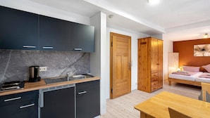 Une cuisine de taille réduite, avec des meubles de couleur sombre, un plan de travail en bois et un évier.