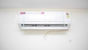 Un condizionatore d'aria bianco con pannello di controllo frontale, collegato a una parete con una presa elettrica visibile.