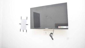 Un televisore fissato al muro, con un cavo di alimentazione e una spina.
