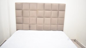Un letto con testiera capitonné in tonalità neutre.