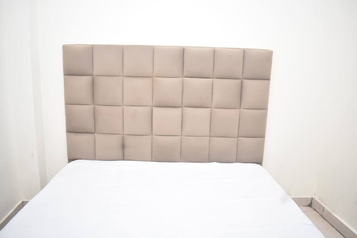A bed with a tufted headboard in a neutral color.