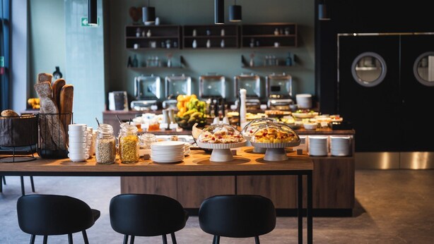 Un'area buffet con diversi piatti, una postazione caffè e un angolo relax con sedute.