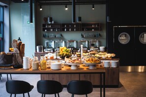 Un'area buffet con diversi piatti, una postazione caffè e un angolo relax con sedute.