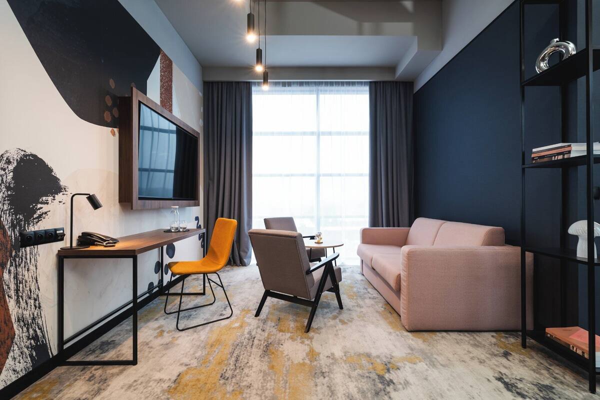 Una sala de estar moderna con un sofá, un sillón y un escritorio con una computadora.
