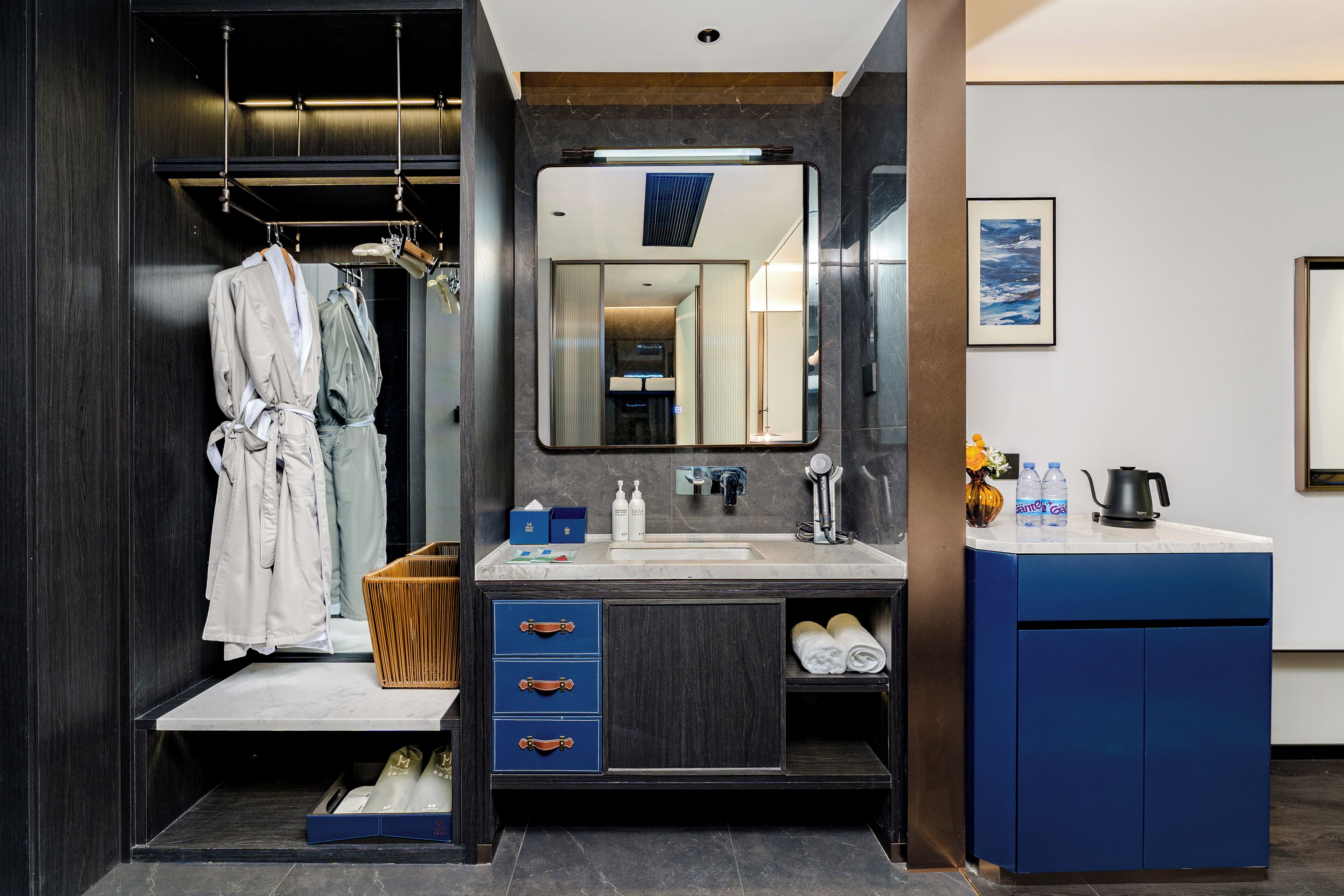 Un baño moderno con un espejo grande, muebles de madera oscura, un tocador con lavabo y un perchero para batas.