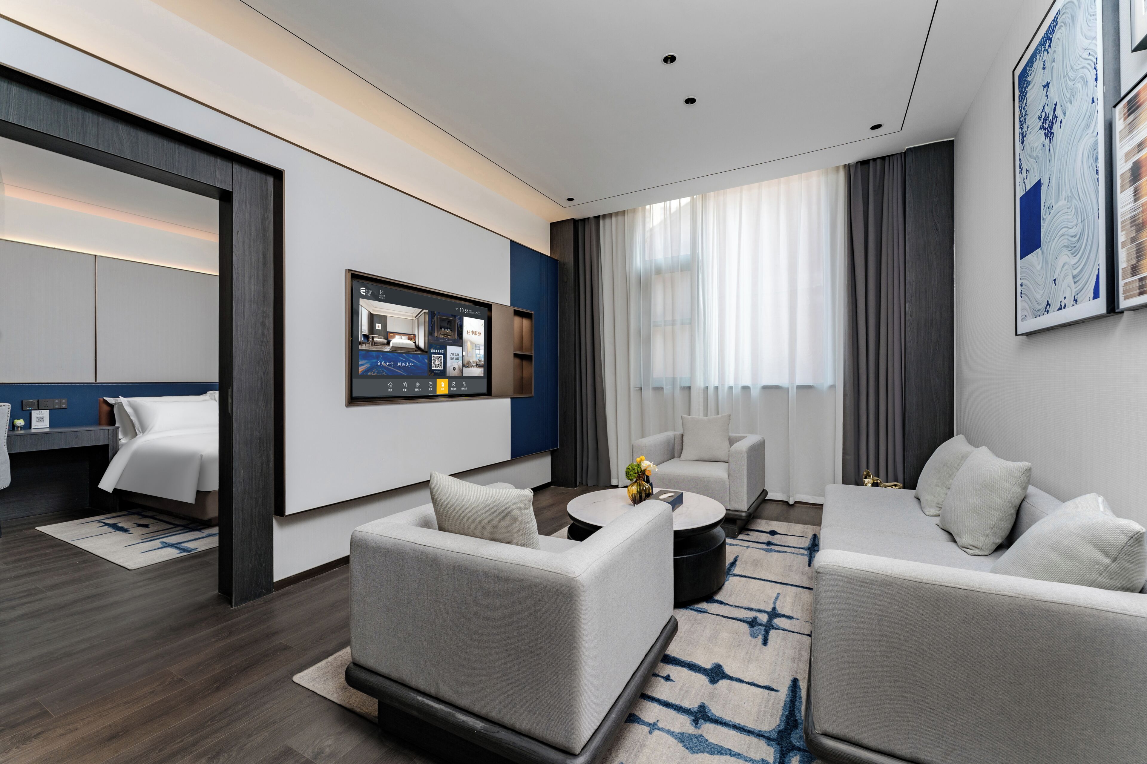 Une chambre d’hôtel moderne équipée d’un lit, de deux canapés, d’une table basse et d’un téléviseur.