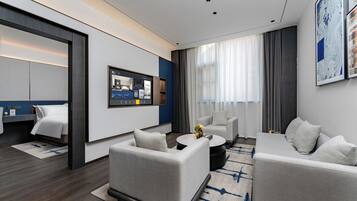 Une chambre d’hôtel moderne équipée d’un lit, de deux canapés, d’une table basse et d’un téléviseur.