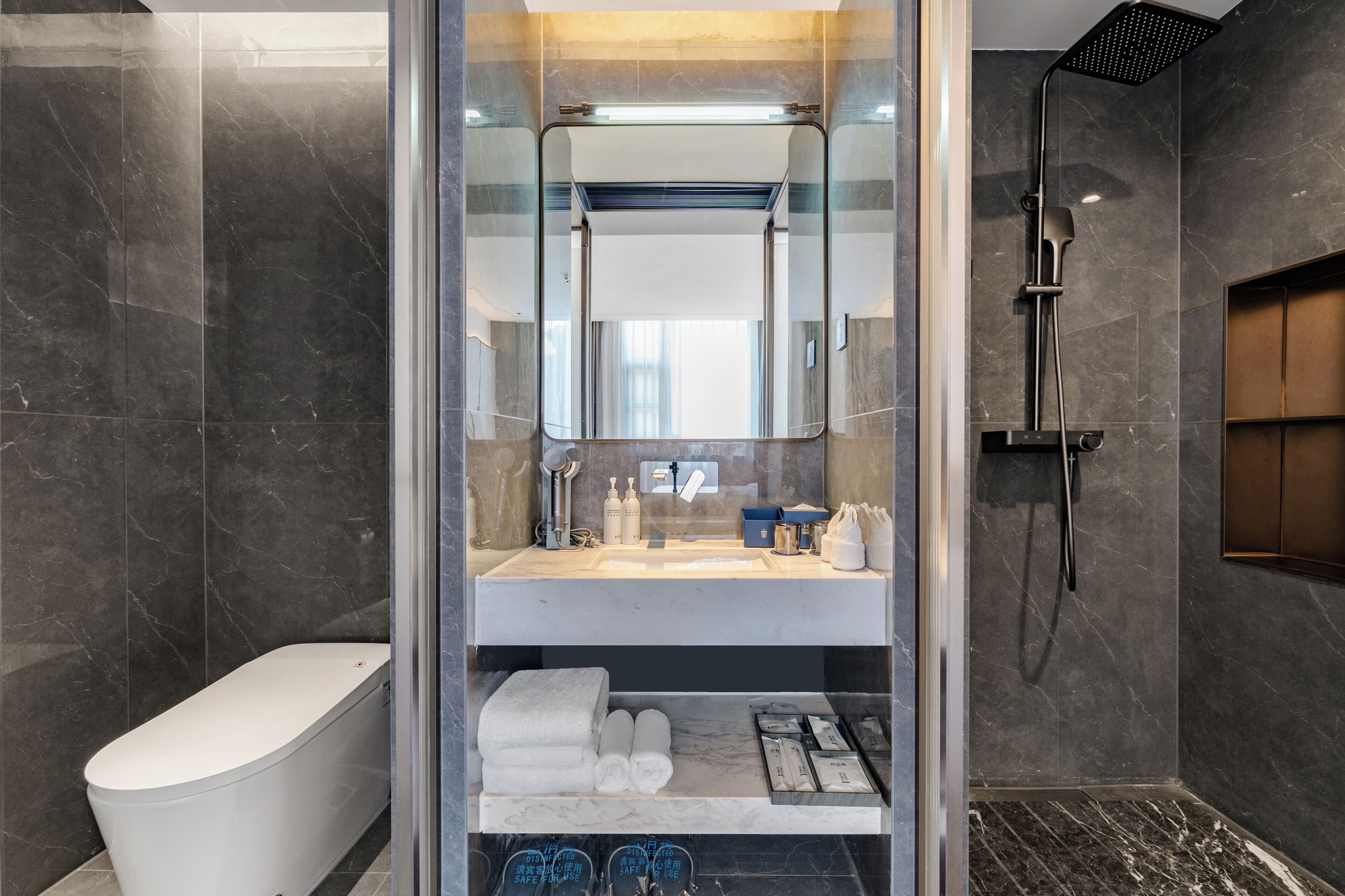 A modern bathroom with a glass-enclosed shower, a toilet, and a vanity with toiletries.