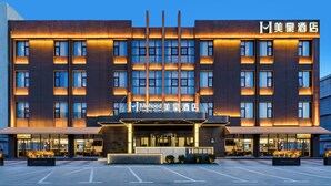 A modern hotel building with a prominent entrance, multiple floors, and illuminated signage.
