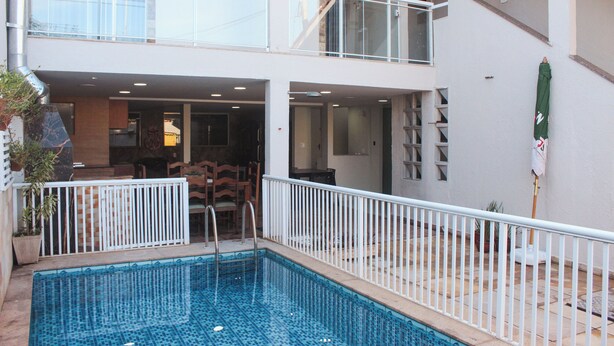 A two-story building with a swimming pool, outdoor seating, and a balcony. - Pousada Porto Maresias (Cabo Frio)