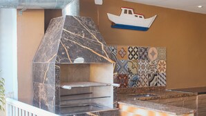 A kitchen with a built-in oven, a hanging boat decoration, and patterned tiles. - Pousada Porto Maresias (Cabo Frio)