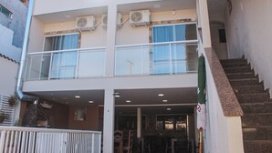A two-story building with a balcony, air conditioning units, and a staircase. - Pousada Porto Maresias (Cabo Frio)