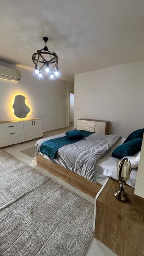 Un dormitorio moderno con cama, mesitas de noche, una lámpara de pared original y un ventilador de techo.