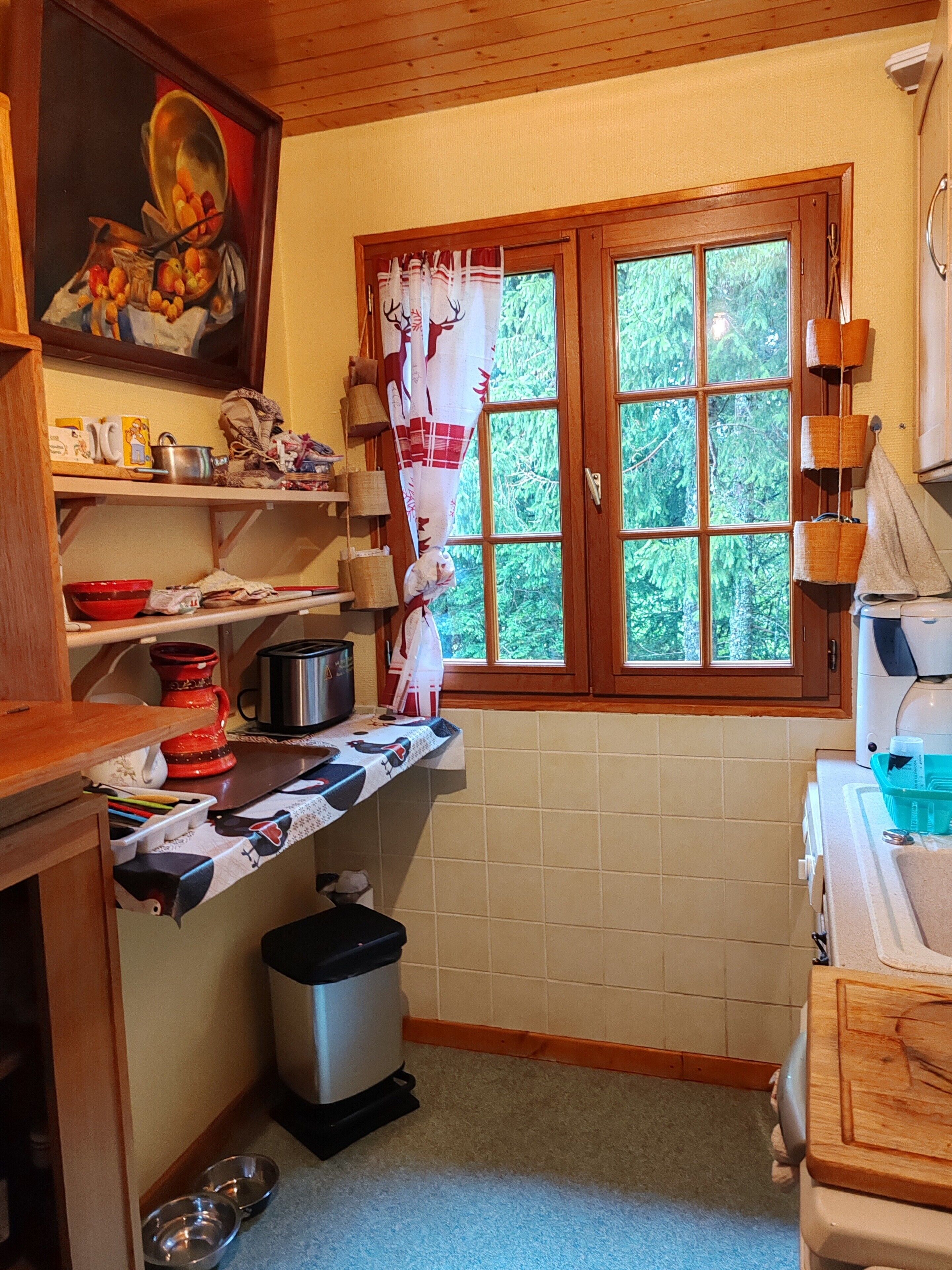 A kitchen with a window, wooden cabinets, a sink, and various kitchen items on the countertops.