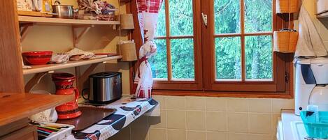 A kitchen with a window, wooden cabinets, a sink, and various kitchen items on the countertops.
