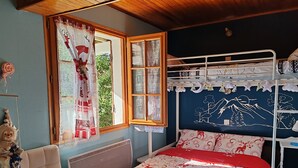 Ein Zimmer mit Etagenbett, einem fenster mit Vorhängen, einem Heizkörper, einem bequemen Sessel und einer Wand mit Wandgemälde.