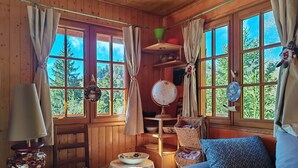 Ein gemütliches Blockhaus-Interieur mit Holzwänden, einem Sofa, einem Tisch mit einer Schüssel, einem Globus und Vorhängen.