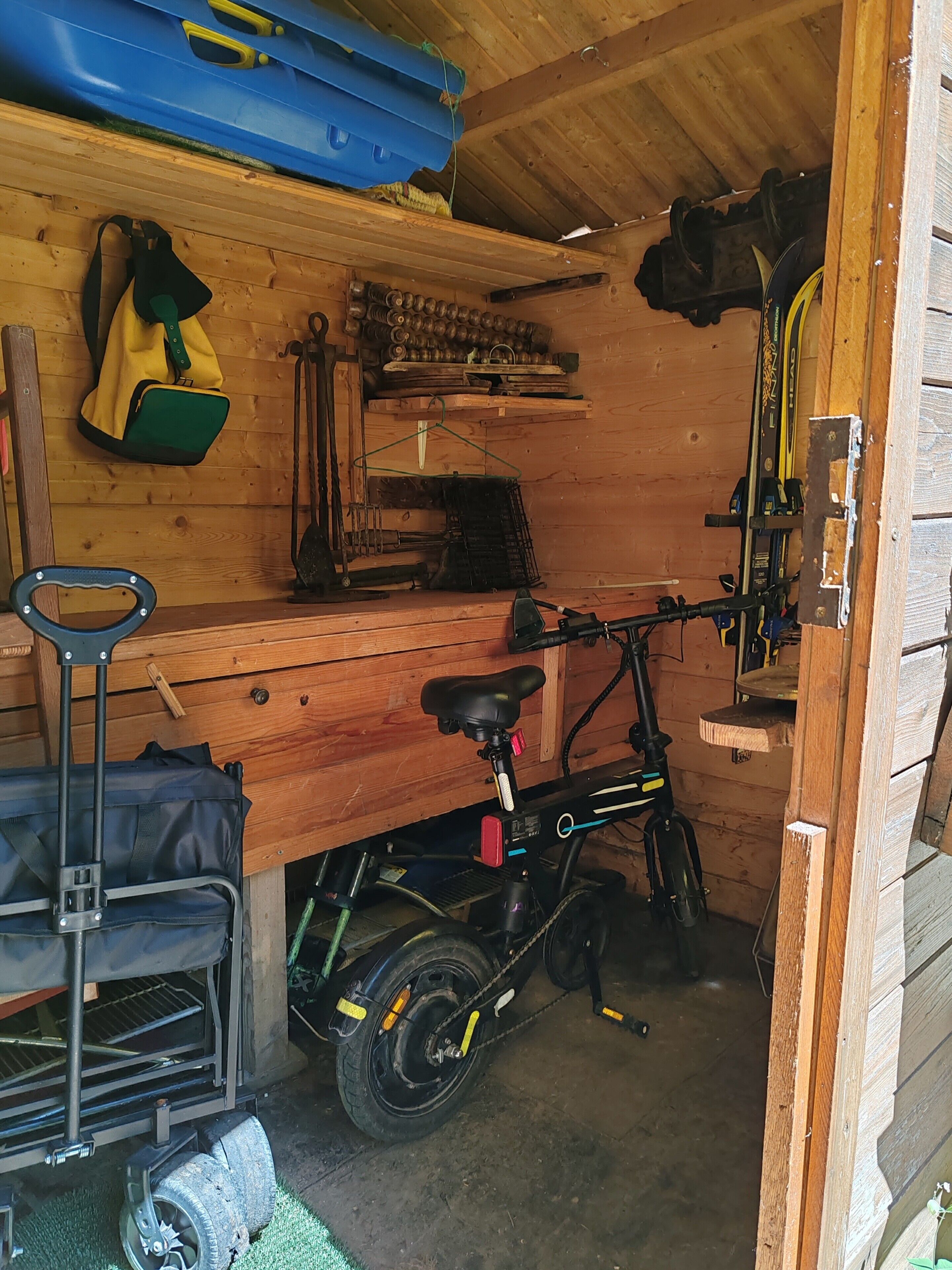 A wooden room with a bicycle, a hanging bag, and a blue object on the wall.