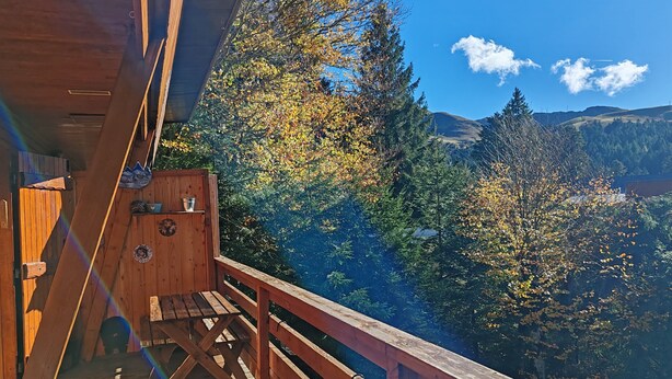 Eine Holzterrasse mit Blick auf Herbstbäume und Berge.