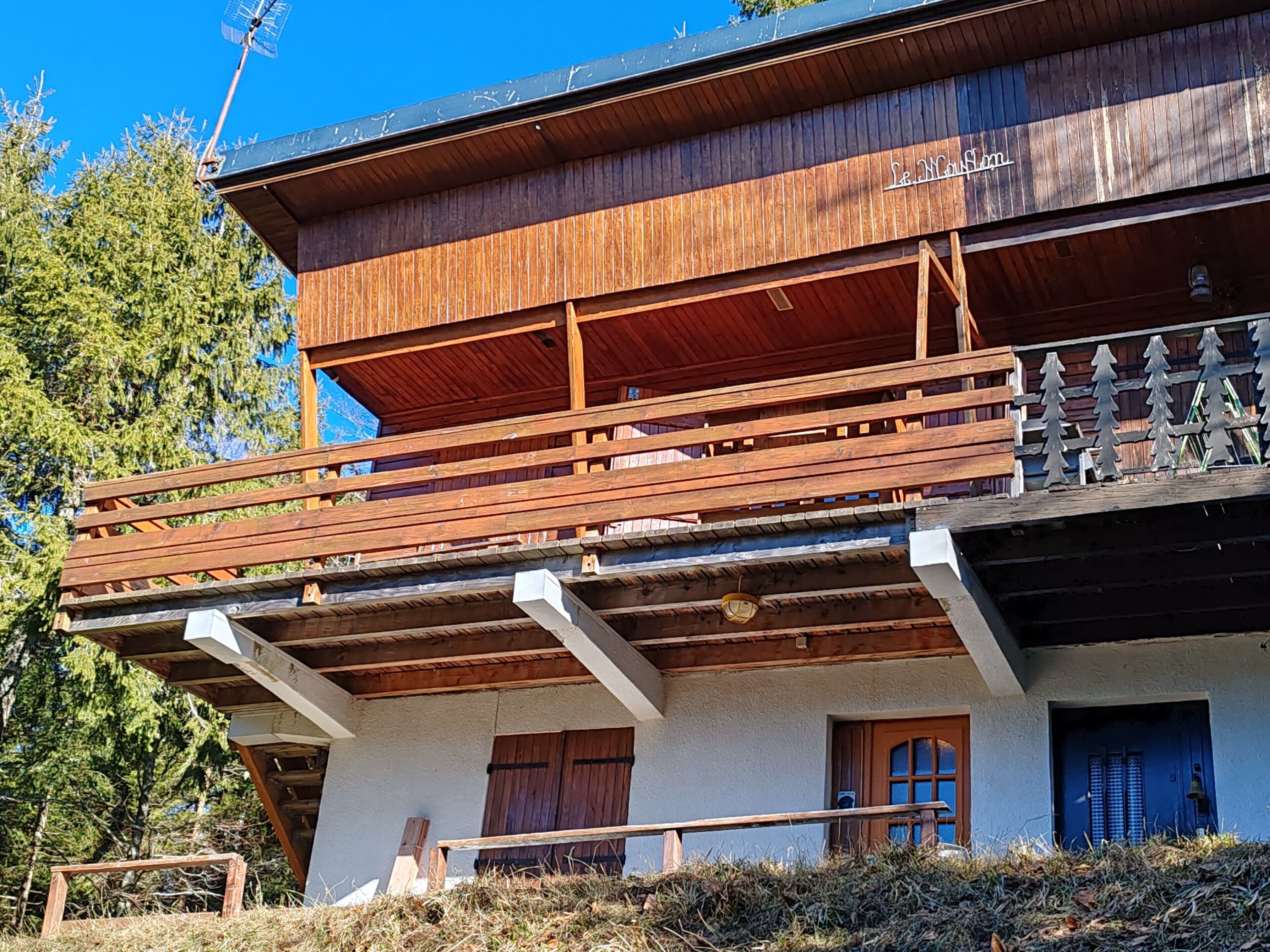 A two-story wooden building with a balcony and a wooden staircase.