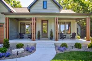 A house with a porch, two chairs, a door, and a window.