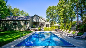 Ein Schwimmbecken mit Liegestühlen und einem Haus im Hintergrund.