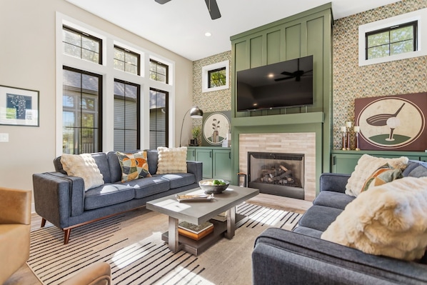 A living room with a fireplace, a sofa, a coffee table, and a television mounted on the wall.