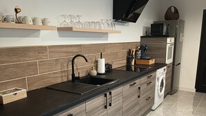 Une cuisine moderne avec un plan de travail noir, des armoires en bois, un lave-vaisselle encastré et un four à micro-ondes.