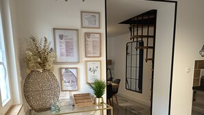 Un espace d’accueil moderne agrémenté d’une pancarte « Bienvenue », de messages de bienvenue encadrés, d’un vase décoratif et d’une table à plateau en verre sur laquelle reposent des paniers en osier.