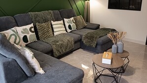 Un salon moderne avec un canapé d’angle, une table basse ronde et un lampadaire.