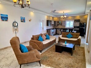 A living room with sofas, a coffee table, and a kitchen in the background.