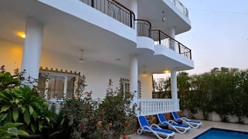 Un immeuble à plusieurs étages doté d’un espace piscine, comprenant des chaises longues et un escalier.