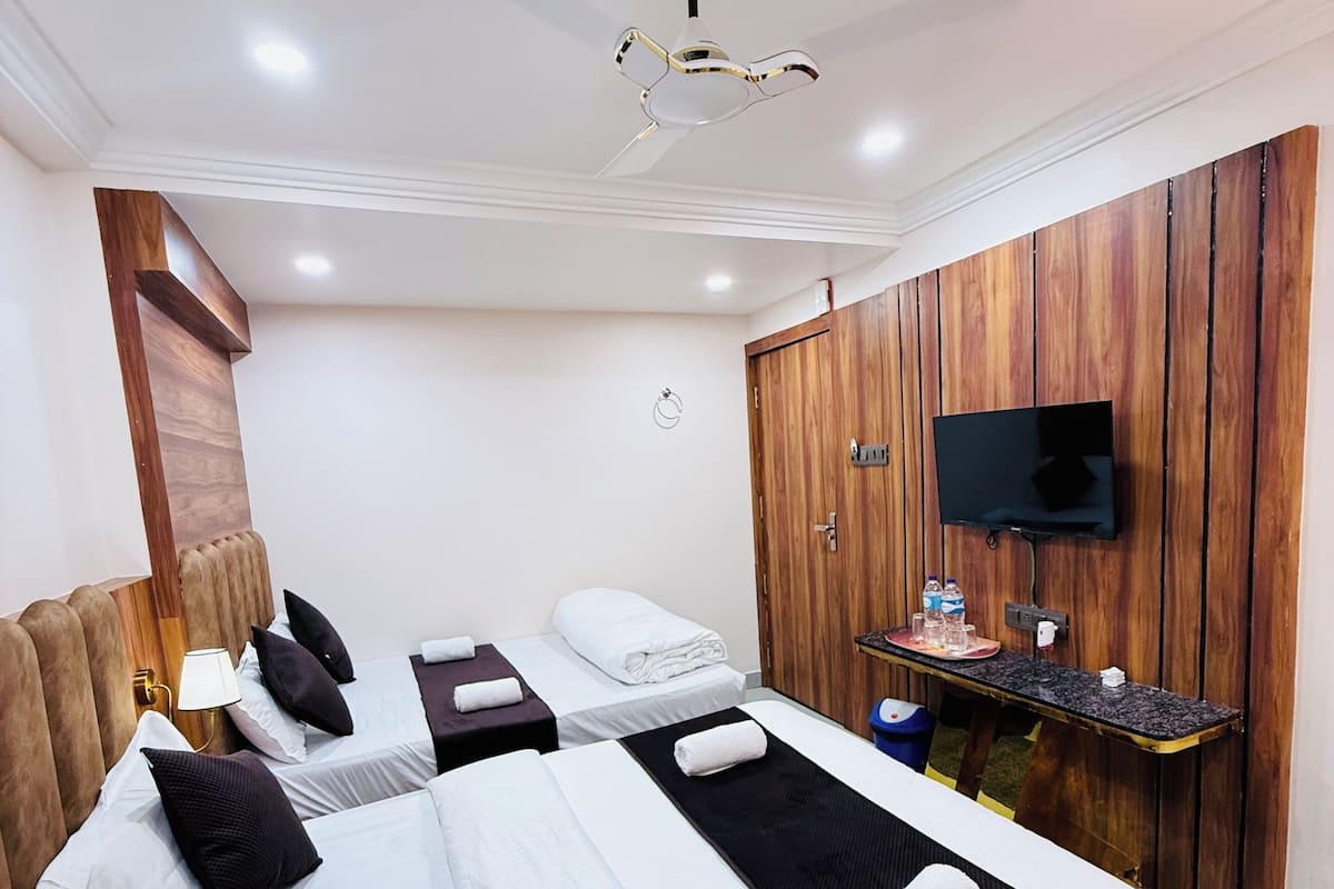 Ein Hotelzimmer mit einem großen Bett, einem an der Holzwand montierten Fernseher, einem Deckenventilator und einem kleinen Tisch mit einer Flasche und Gläsern.