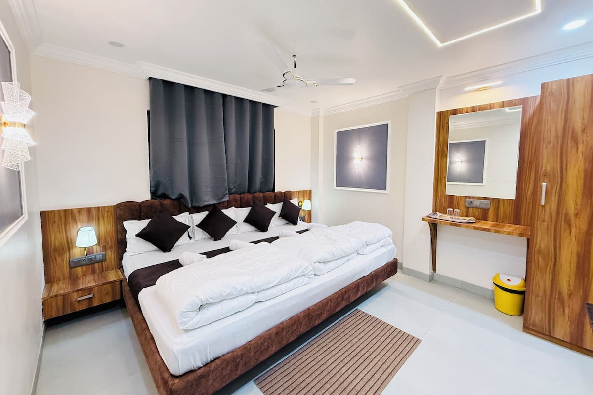 Ein modernes Schlafzimmer mit einem großen Bett, einem Holz-Kopfende, Nachttischlampen, einem Deckenventilator, einem Spiegel und einem kleinen Tisch mit einem Papierkorb.