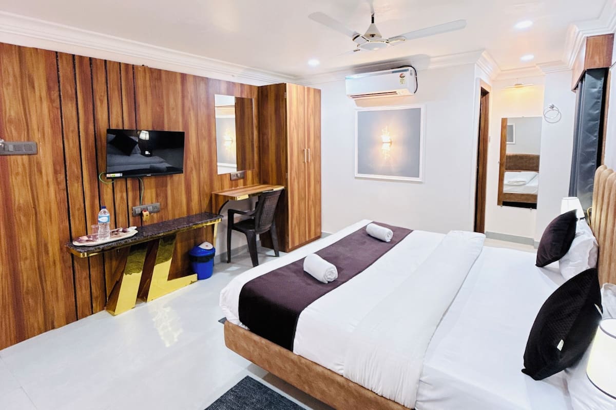 Ein Hotelzimmer mit Bett, Schreibtisch, Stuhl, Fernseher und einem kleinen Badebereich.